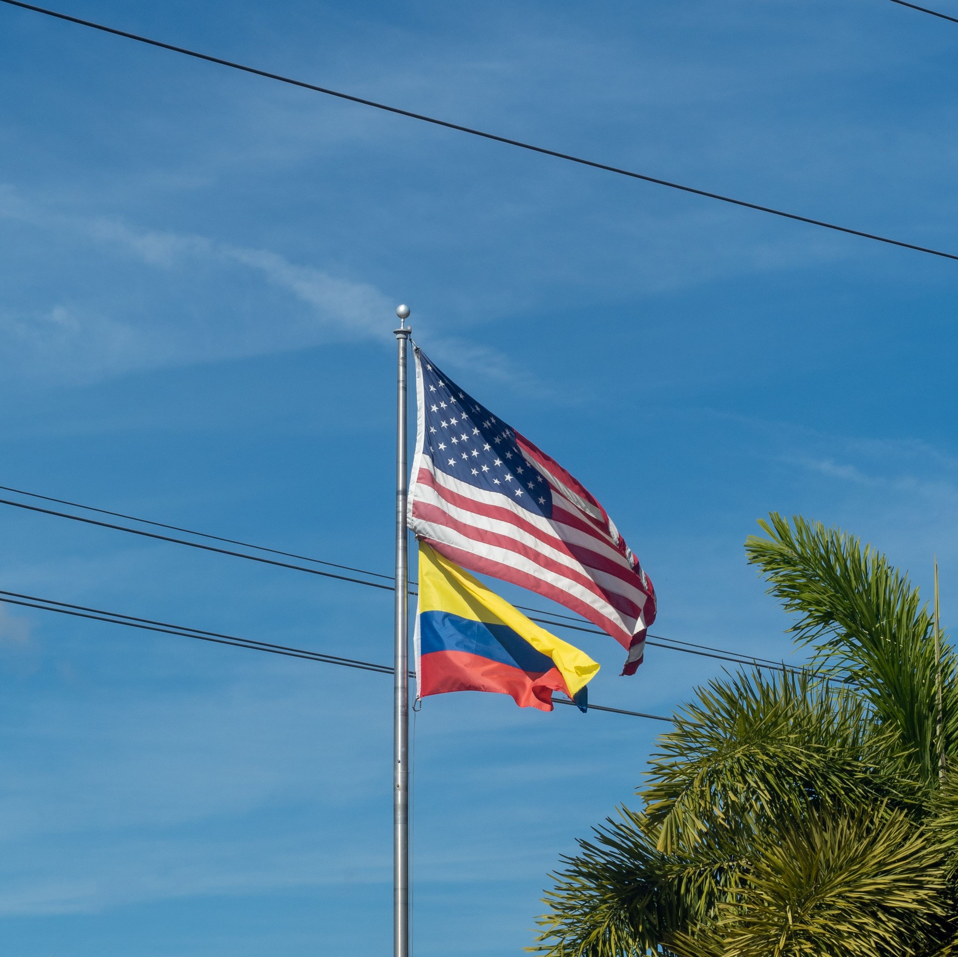 Toma de ángulo bajo de las banderas de Colombia y Estados Unidos en postes
